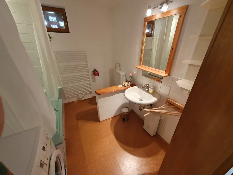 Badezimmer der Ferienwohnung mit Holzspiegel und Handtuchheizkörper