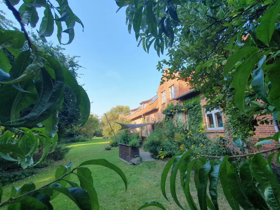 Garten des Resthofs in Groß Heide mit Rasen, Hochbeet und Sonnensegel