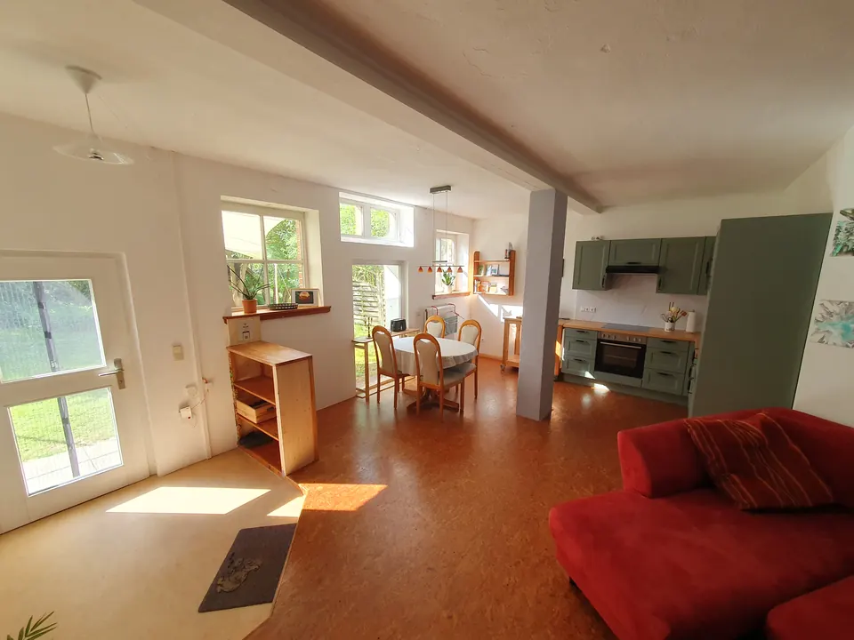 Wohnbereich mit rotem Sofa und Blick ins Grüne